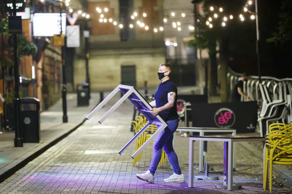 A bar worker packs tables and chairs away