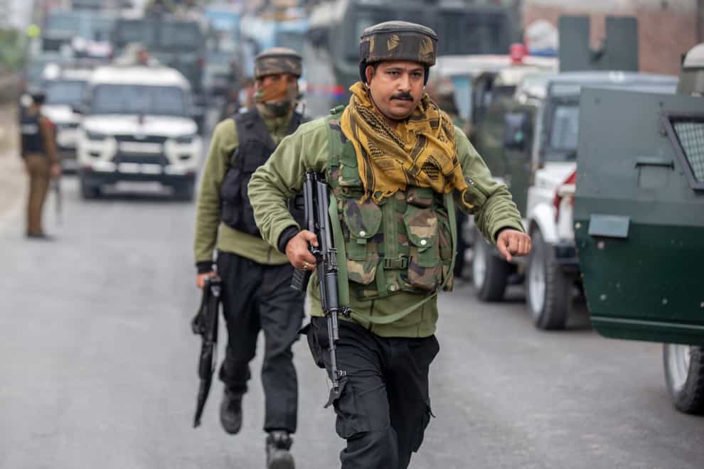 Indian police men rush towards their armoured vehicle near the site of a gun battle on the outskirts of Srinagar (Dar Yasin/AP)