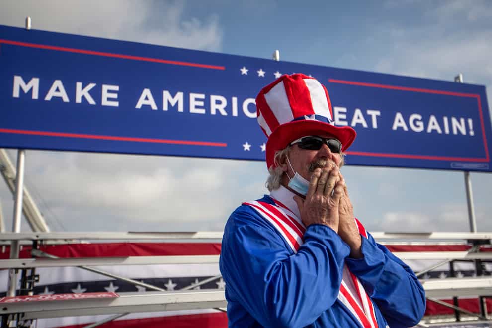 A Trump supporter stands under a Make America Great Again banner