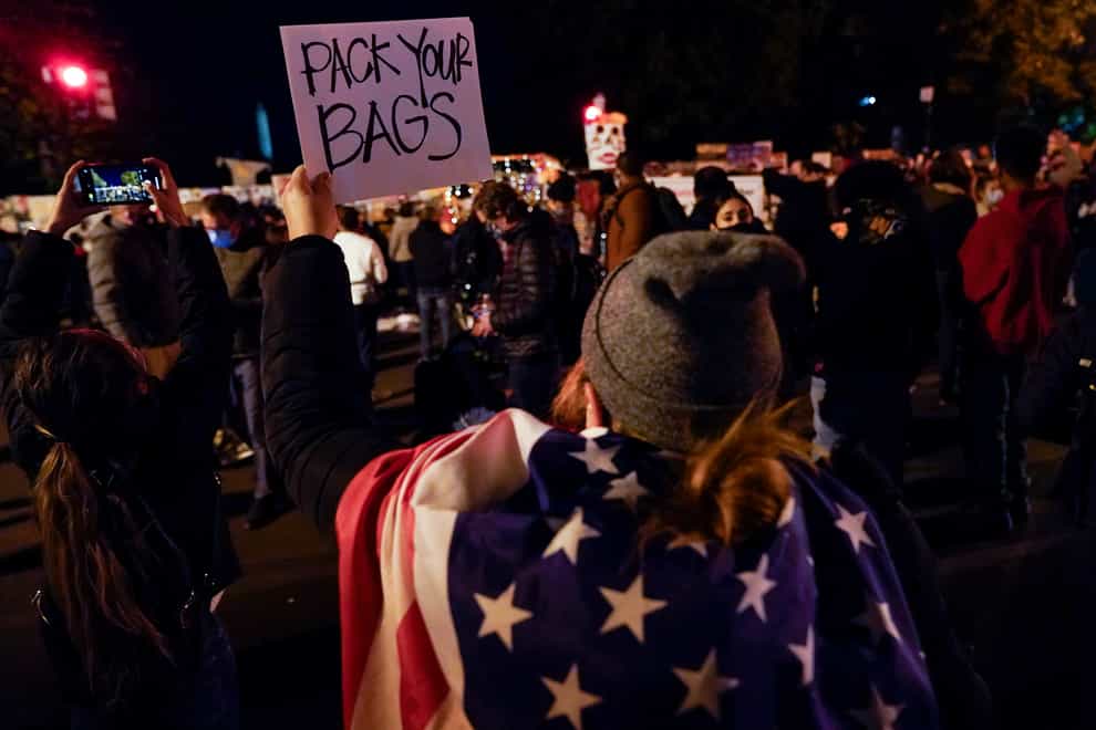 A demonstrator holds up a sign while watching election returns outside the White House