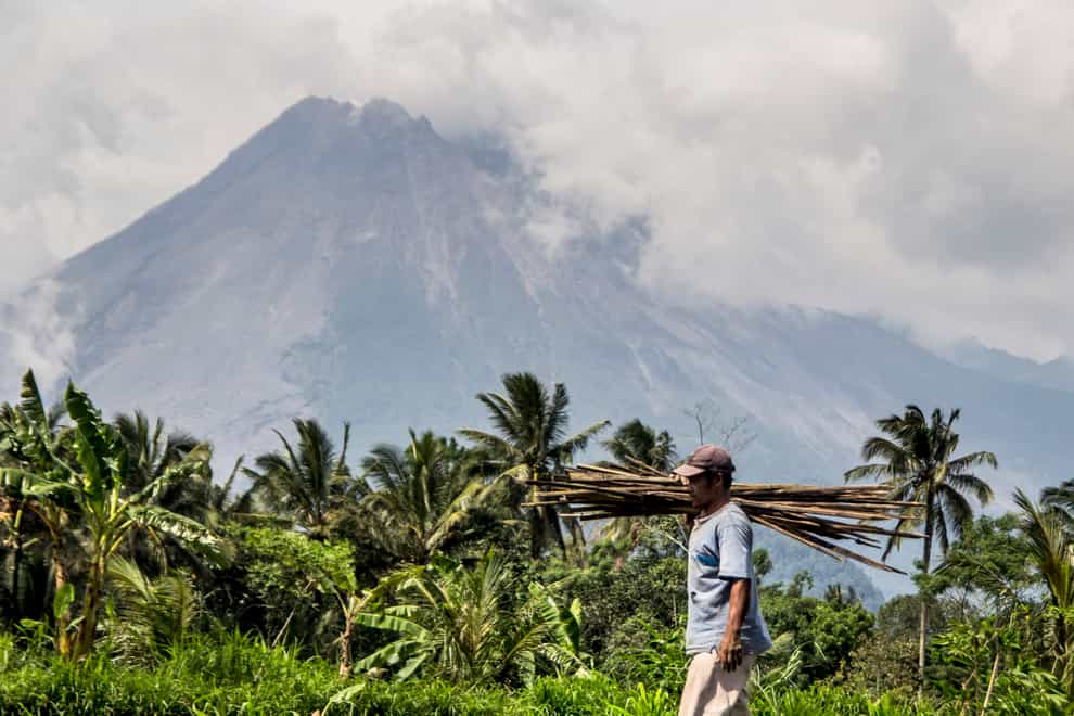 A farmer walks on his field as Mount Merapi is seen in the background (Slamet Riyadi/AP)