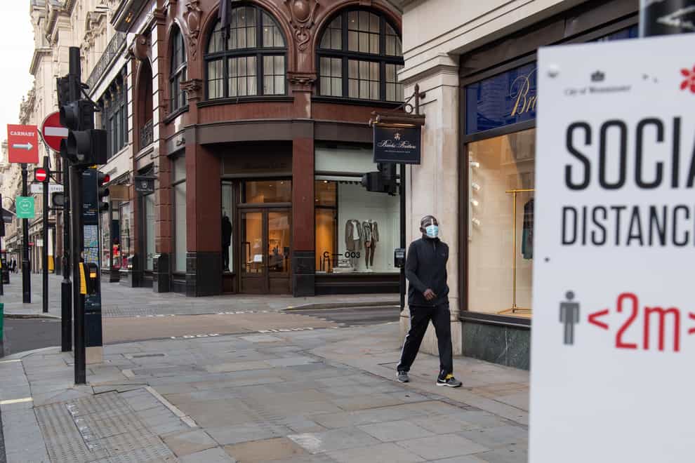 A man wearing a protective visor passes closed shops on Regent Street