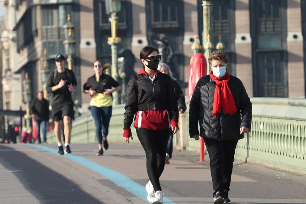 People wearing face masks walking along Westminster Bridge