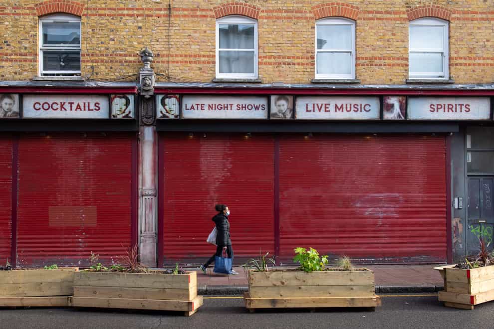 A woman passes a shuttered bar in Brixton, south London