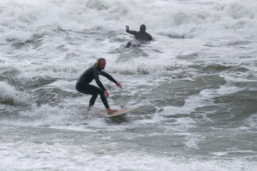 People surfing in the sea off Boscombe beach in Dorset