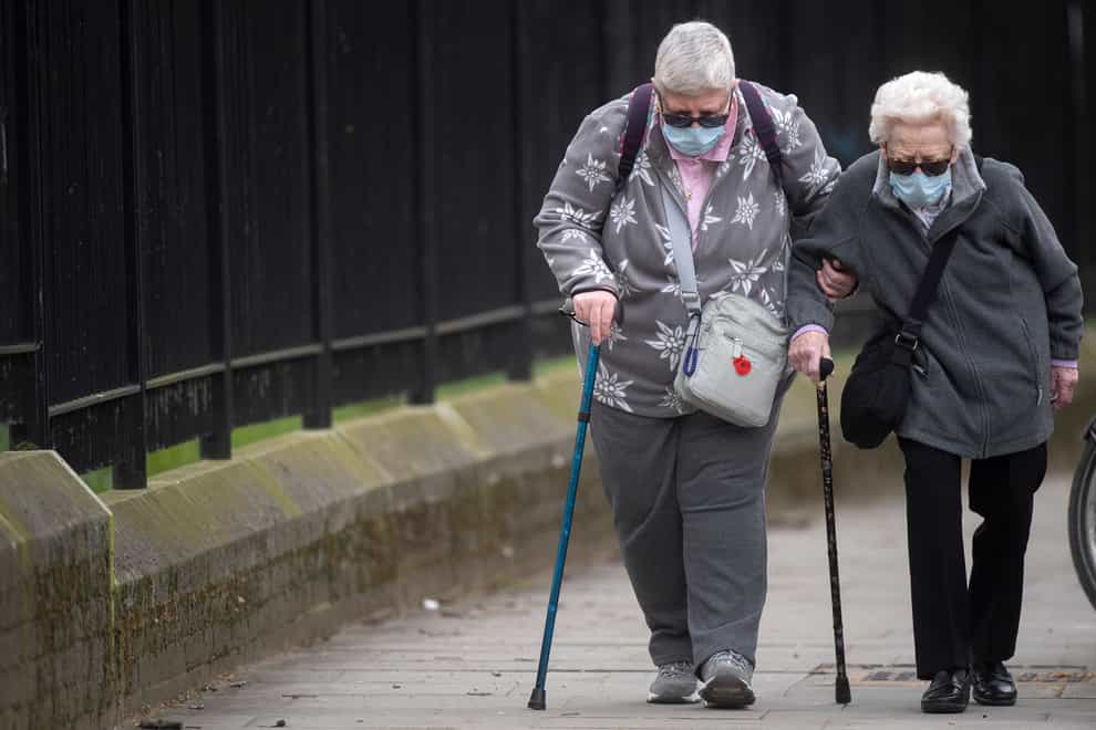 Two elderly women wearing protective face masks walk in Westminster