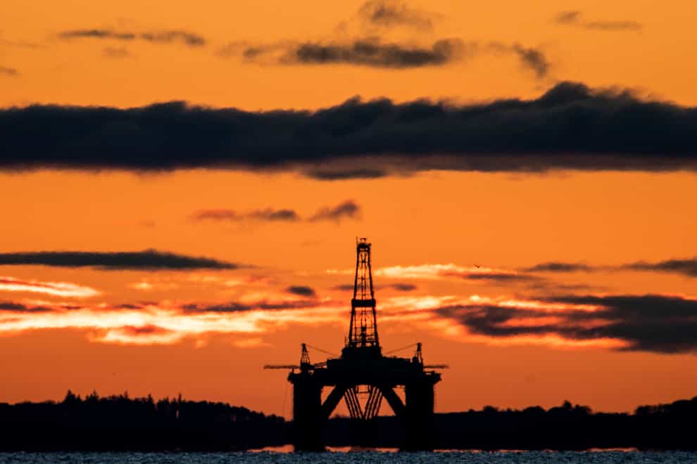 The sun rises behind a redundant oil platform