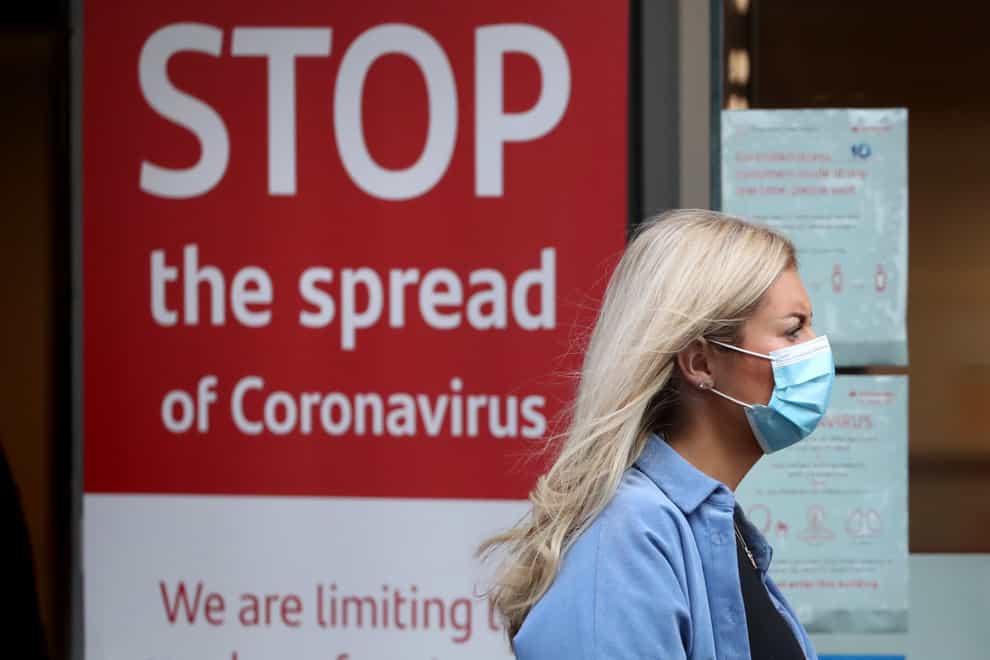Woman with mask in front of coronavirus sign