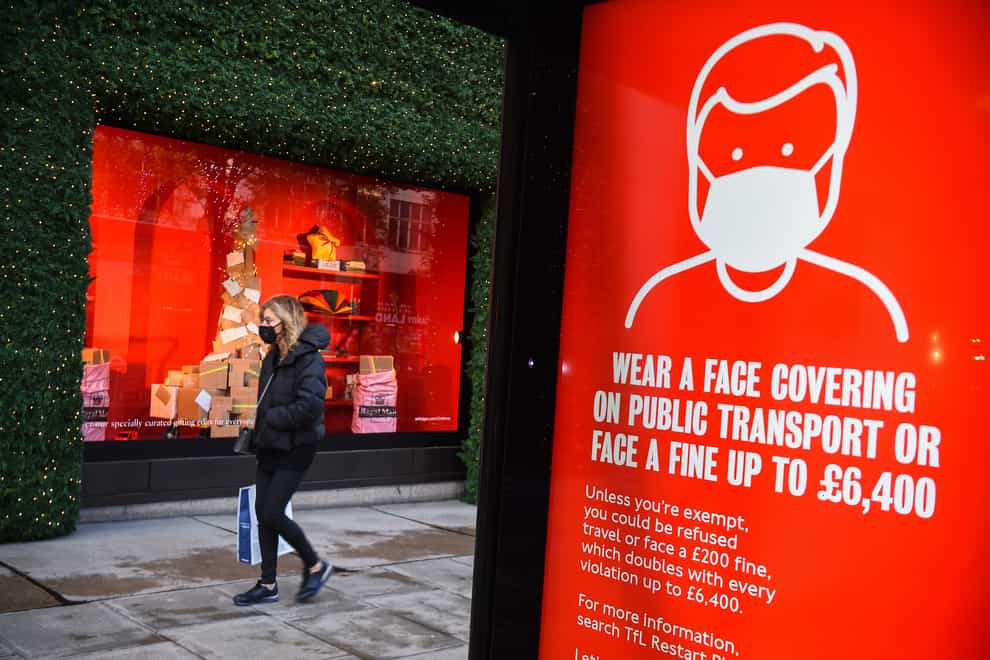 A woman wearing a face mask passes a screen advising the wearing of face masks on Ox