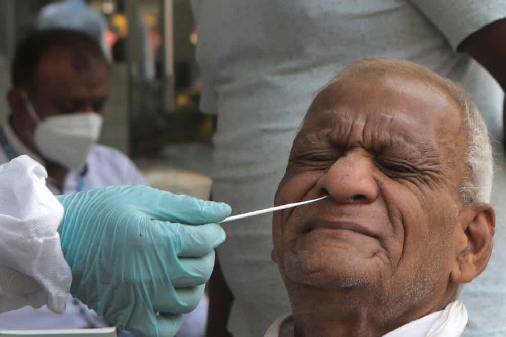 A health worker takes a swab sample to test for Covid-19 on a street in Mumbai, India (Rajanish Kakade/AP)