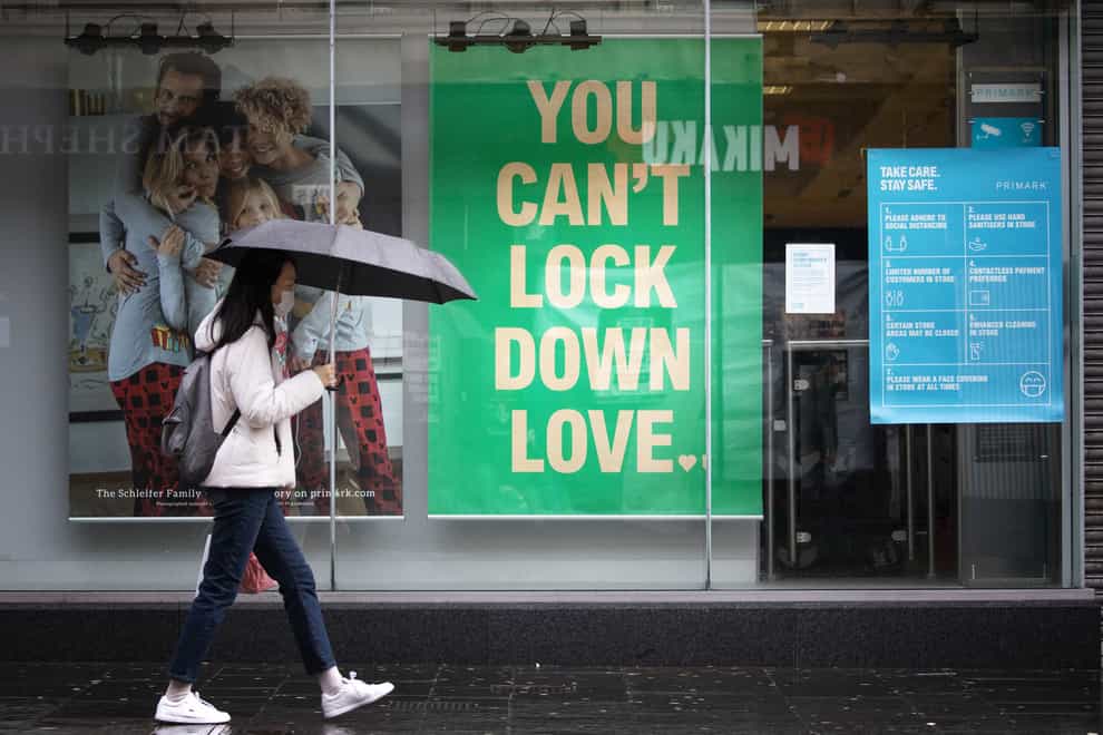 A woman walks past a shop sign that reads 'you can't lock down love'