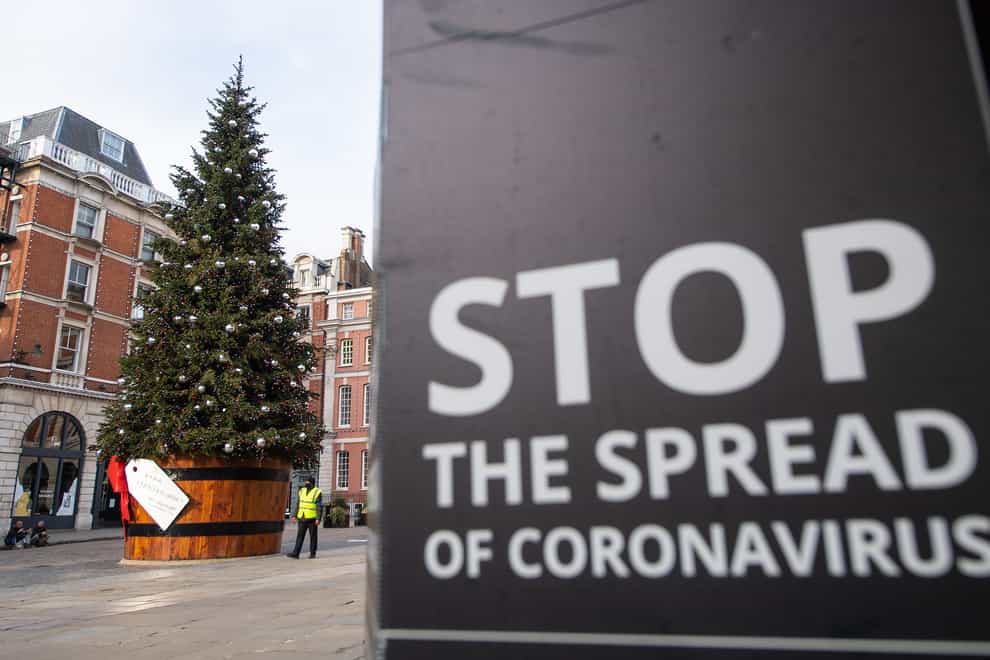 A Christmas tree is seen alongside coronavirus signage in Covent Garden
