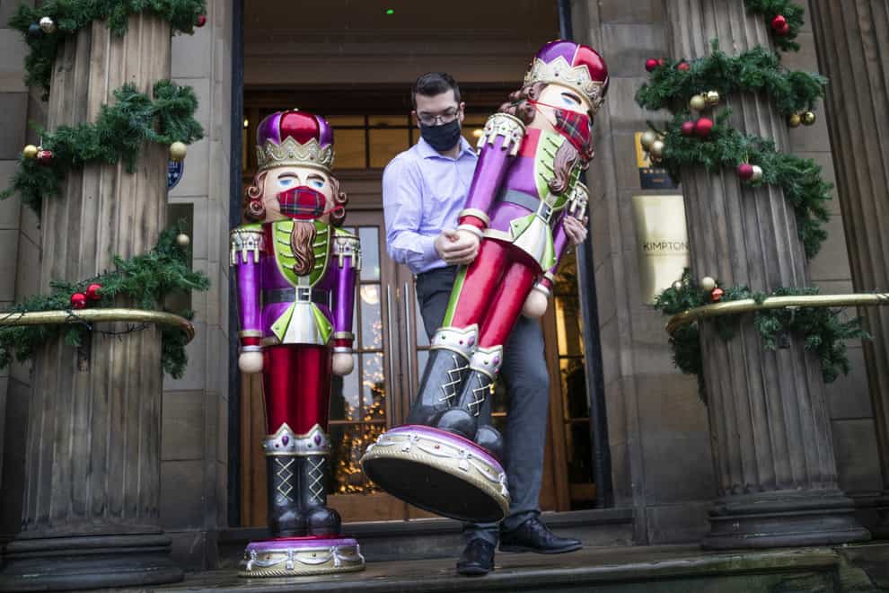 A worker in a face mask places Christmas Nutcrackers outside a hotel