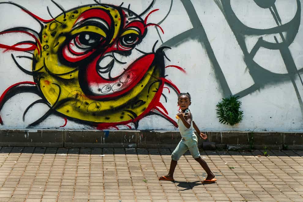 A child walks past a Covid-19 graffiti in Soweto’s Orlando West township near Johannesburg (Jerome Delay/AP)Irus outbreak Africa