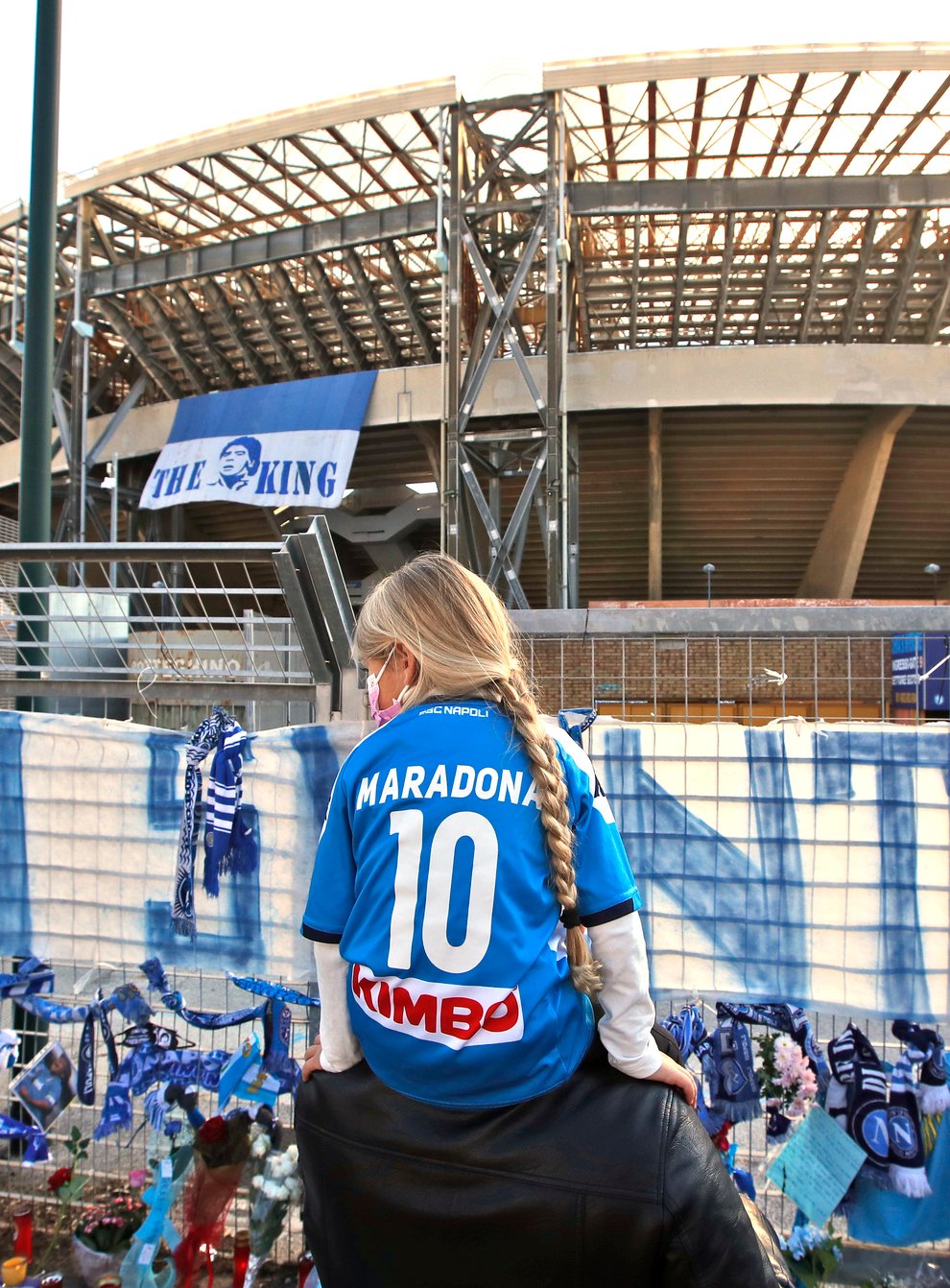 A girl wearing a Maradona number 10 shirt looks at the tributes at Napoli's San Paolo Stadium