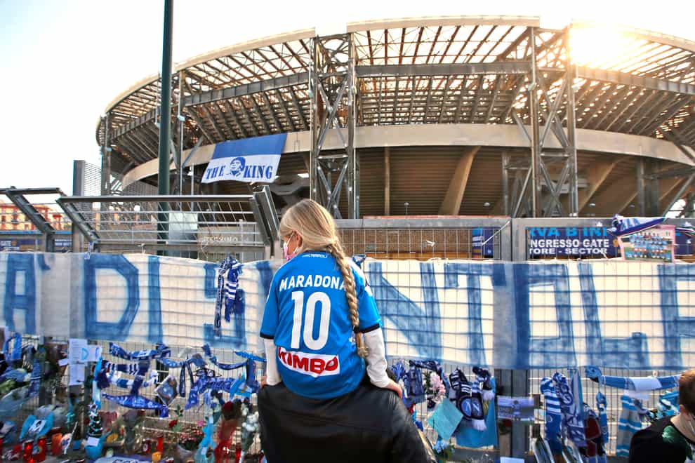 A girl wearing a Maradona number 10 shirt looks at the tributes at Napoli's San Paolo Stadium