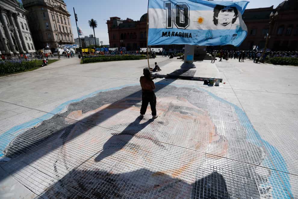 A man waves a flag with the face of Diego Maradona at Plaza de Mayo, outside the presidential palace in Buenos Aires