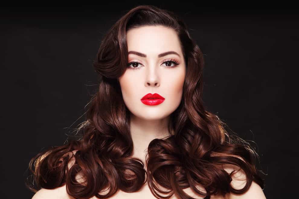 Portrait of young beautiful woman with long curly hair and red lipstick