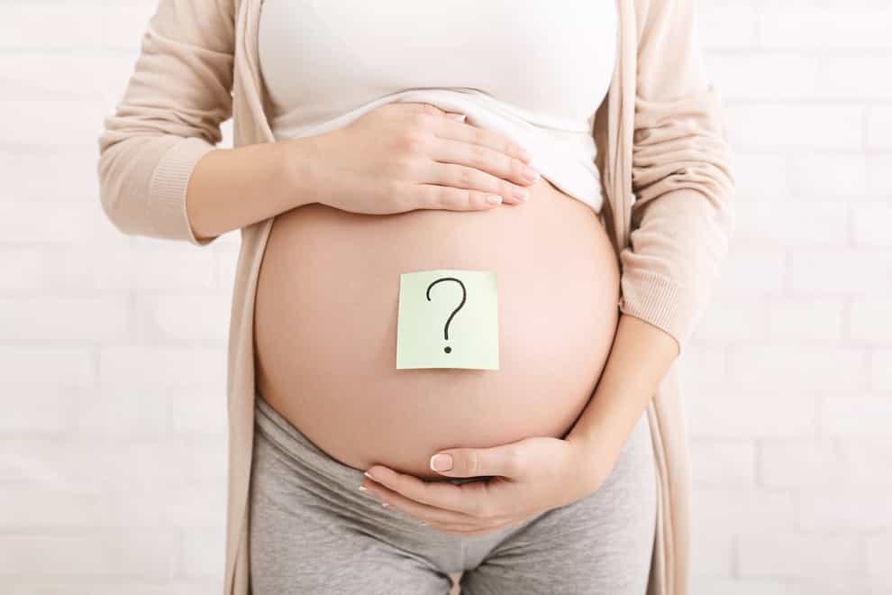 Pregnant woman belly with question mark on paper stickers
