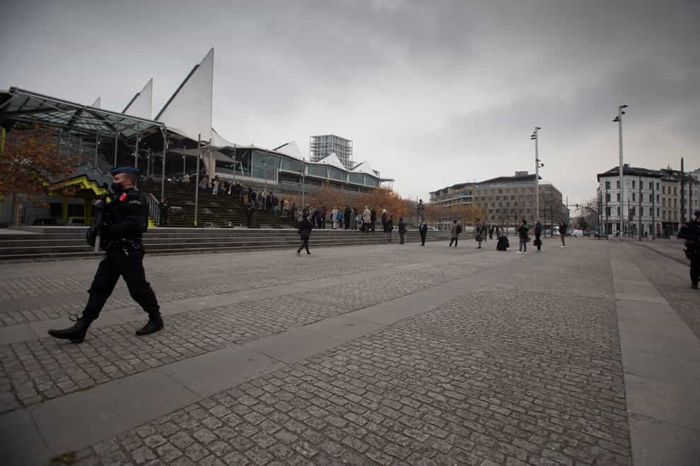 People wait in a queue as police patrol outside of the courthouse in Antwerp, Belgium (Virginia Mayo/AP)