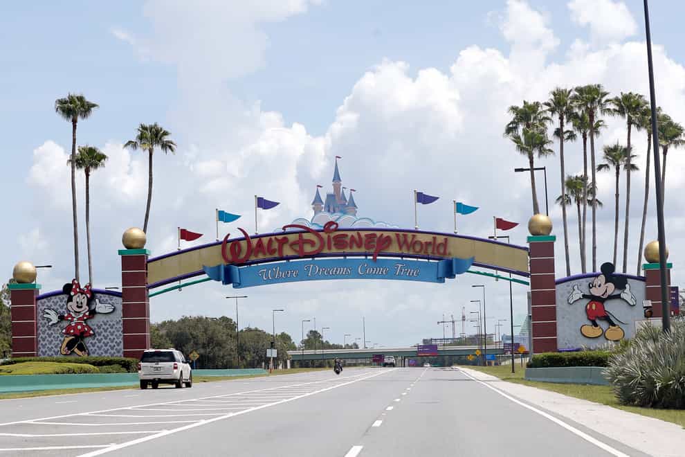Cars drive under a sign greeting visitors near the entrance to Walt Disney World, in Lake Buena Vista, Florida (Jon Raoux/AP)