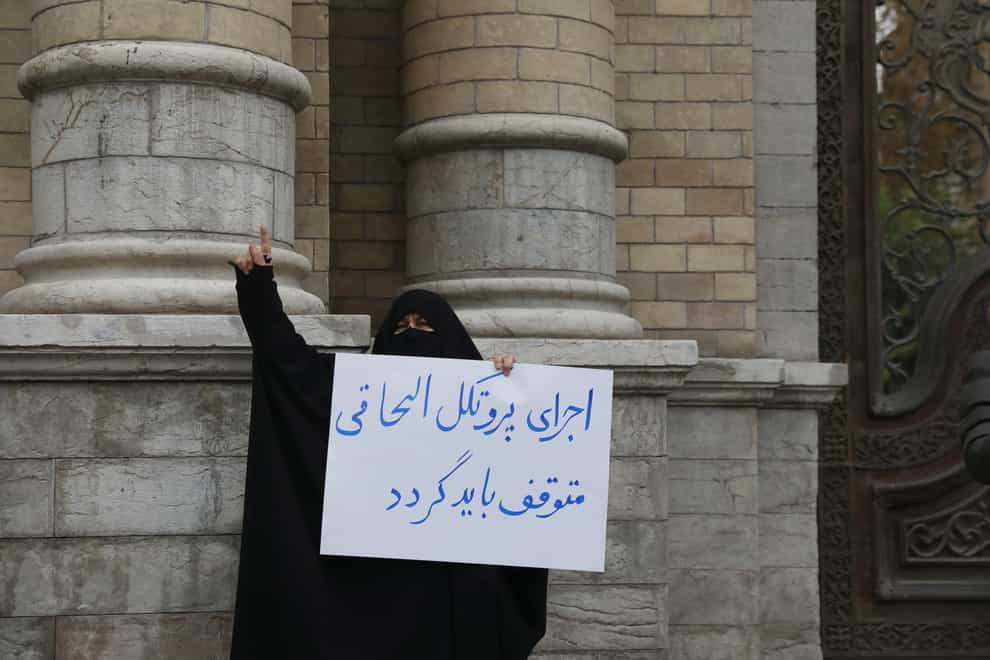 A protester holds a placard which reads in Persian: ” Stop implementation of the Additional Protocol (of the IAEA)” during a gathering in front of Iranian Foreign Ministry (Vahid Salemi/AP)