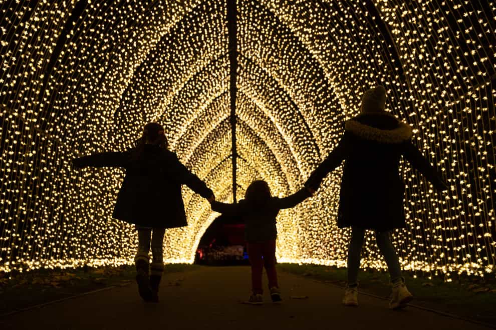 Lulu Kingstone, nine, Alfred Alejandro Dudely-Mira, three, and Elena Kingstone, 11, walk through the Cathedral of Light, a pealight-lit tunnel of lights, during a preview for Christmas at Kew at the Royal Botanic Gardens in Kew, London