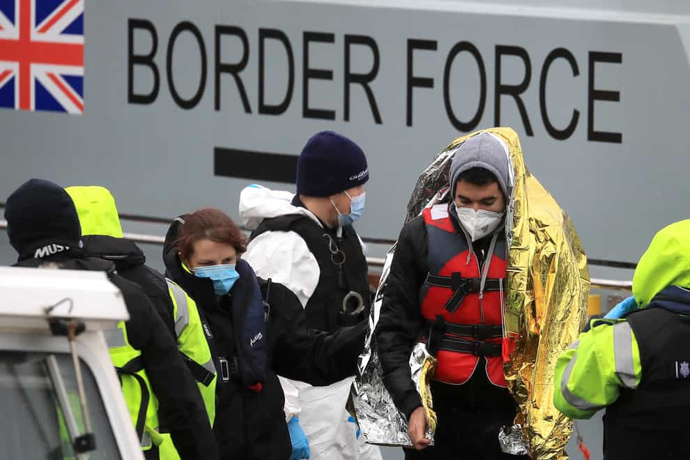A man is helped by a Border Force officer as a group of people thought to be migrants are brought in to Dover, Kent, onboard a Border Force vessel following a small boat incident in the Channel