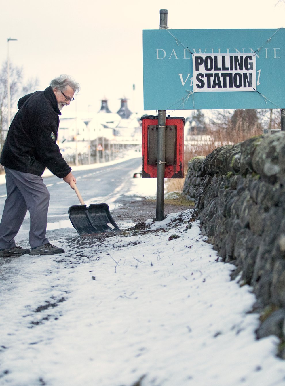 A man clears snow outside a polling station in Dalwhinnie in the Cairngorms, during the 2019 general election (Jane Barlow/PA)