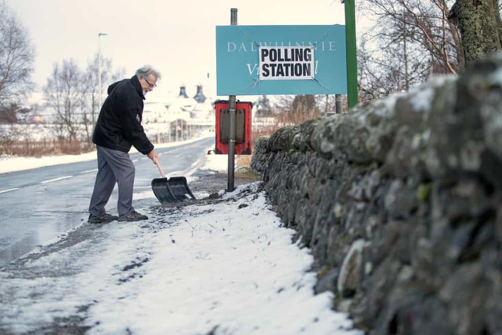 A man clears snow outside a polling station in Dalwhinnie in the Cairngorms, during the 2019 general election (Jane Barlow/PA)