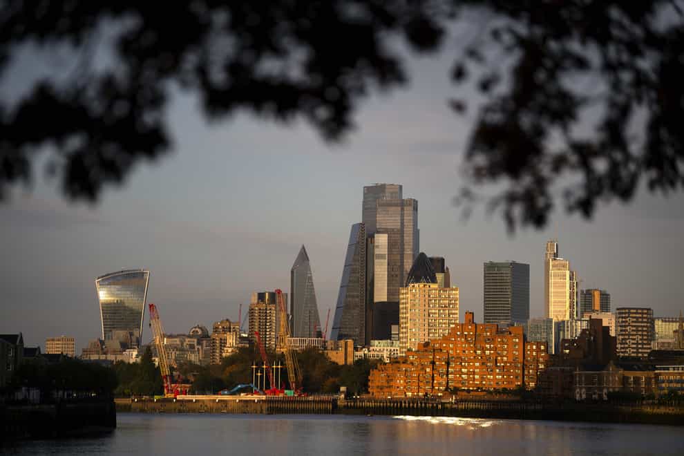 The skyline of the City of London lit by sunrise.