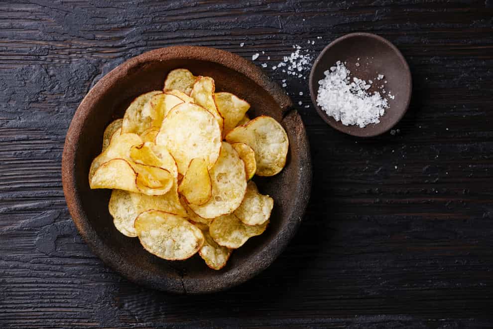 Homemade crispy Potato chips and sea   salt on dark wooden background