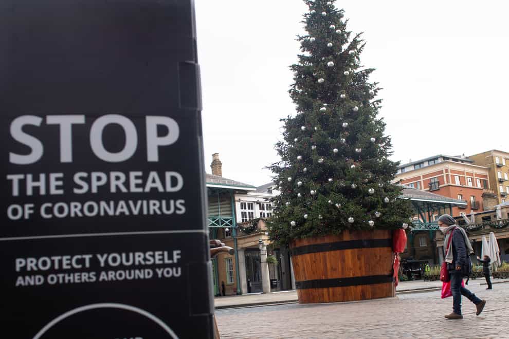 A Christmas tree is seen alongside coronavirus signage in Covent Garden, London