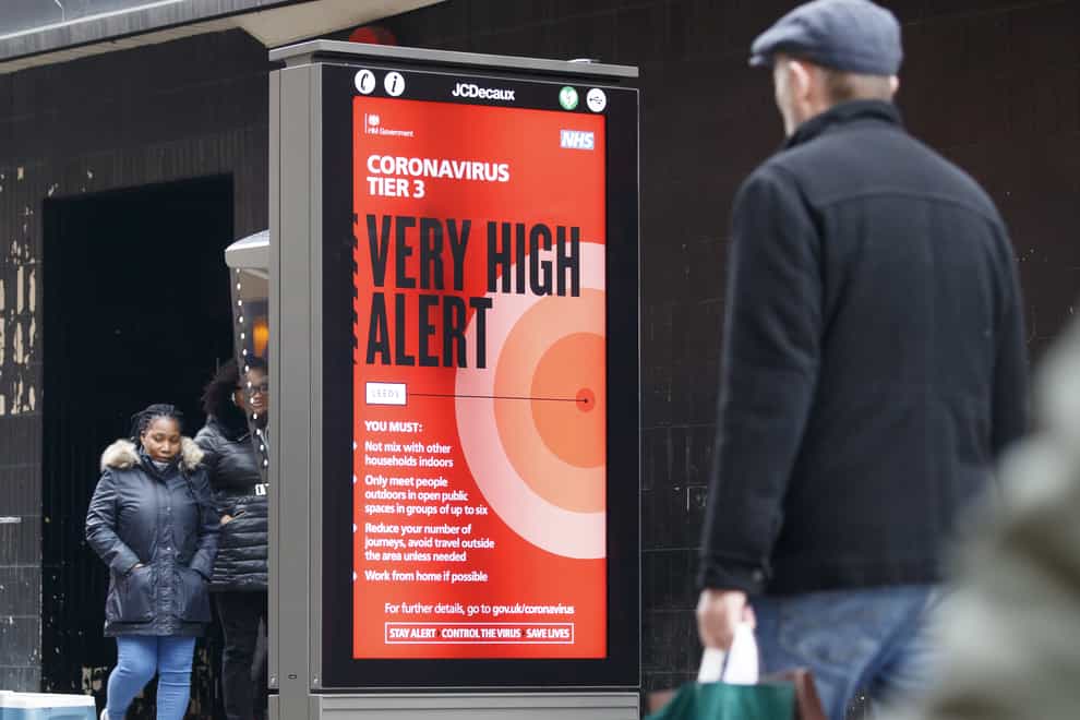 Christmas shoppers walk past a coronavirus Tier 3 Very High Alert sign in Leeds (Danny Lawson/PA)