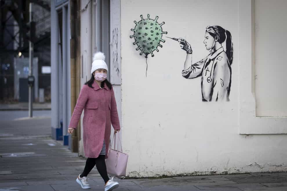 A member of the public walks past coronavirus artwork created by street artist The Rebel Bear in Edinburgh city centre