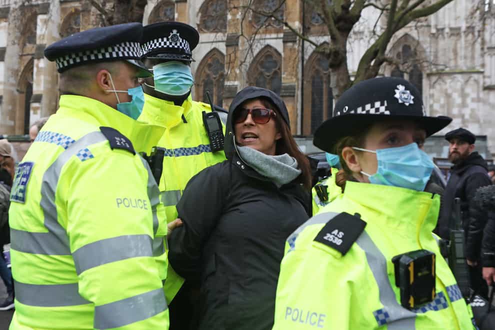 Police detain a woman taking part in a protest in Parliament Square, London