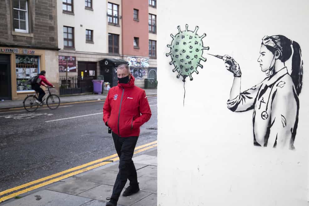 A member of the public walks past Covid-19 artwork in Edinburgh
