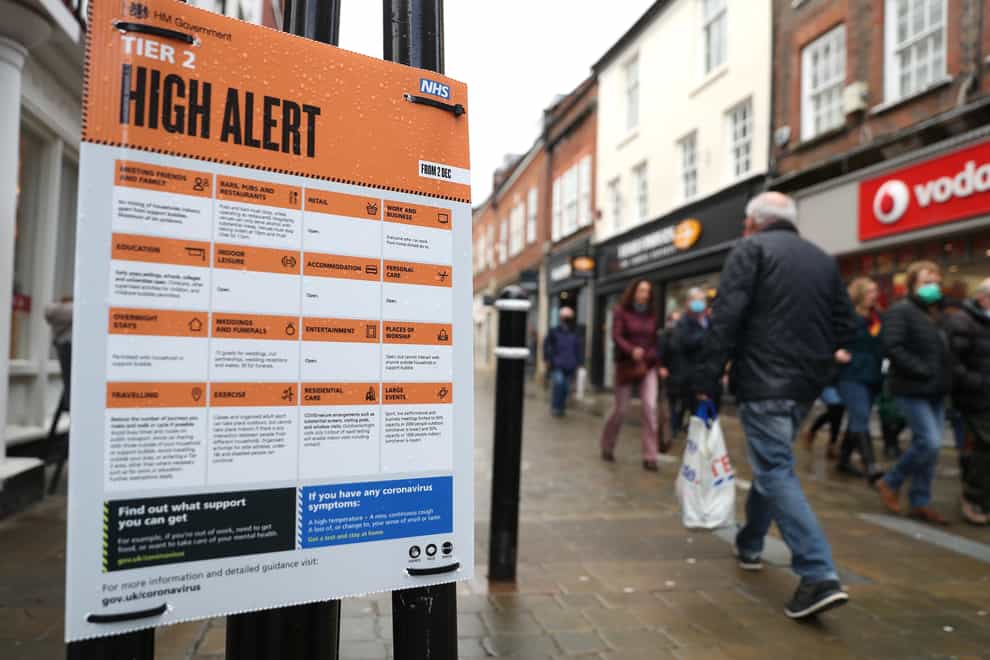 Christmas shoppers make their way past a Tier 2 High Alert sign in Winchester (Andrew Matthews/PA)
