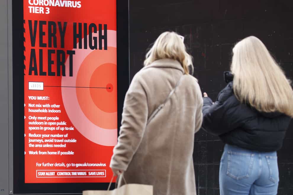 Christmas shoppers walk past a coronavirus Tier 3 sign in Leeds
