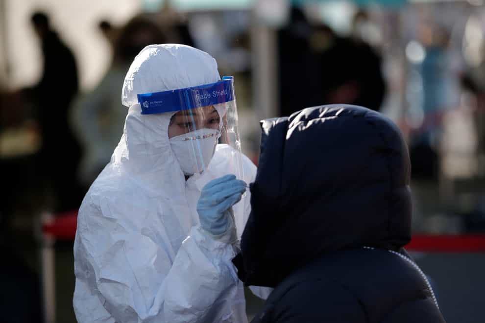 A medical worker wearing protective gear takes a sample from a woman during a Covid-19 testing in Seoul, South Korea