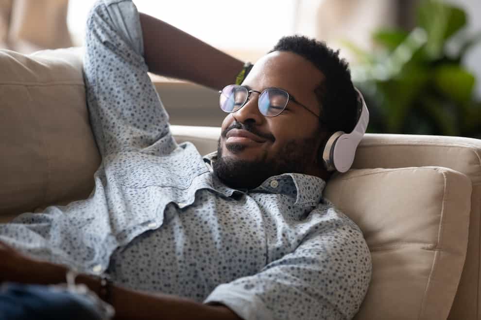 Man listening to a podcast on a sofa (iStock/PA)