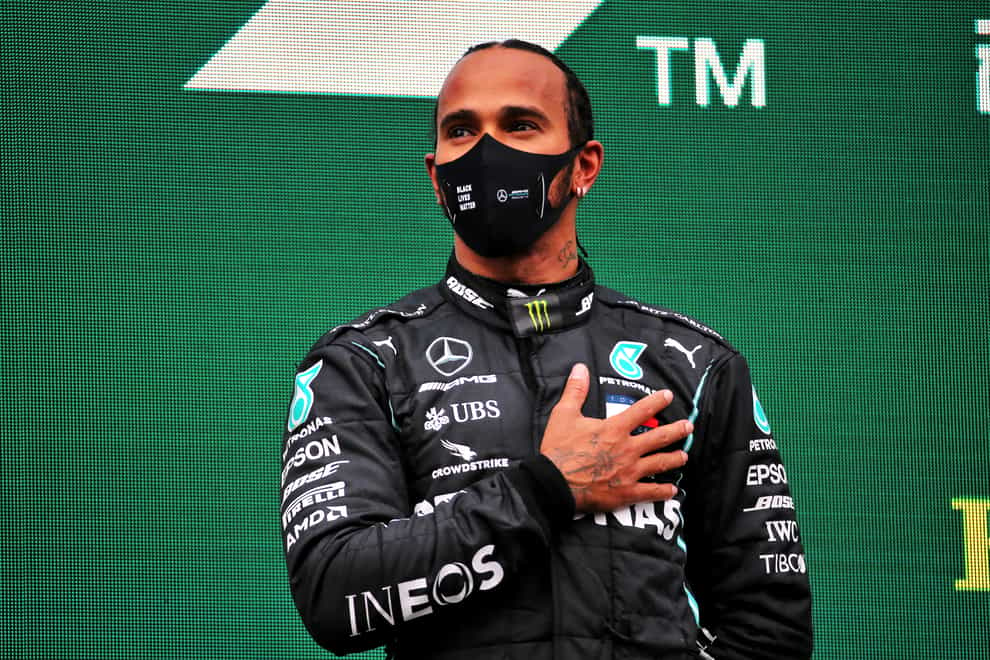 Lewis Hamilton stands with his hand on his heart