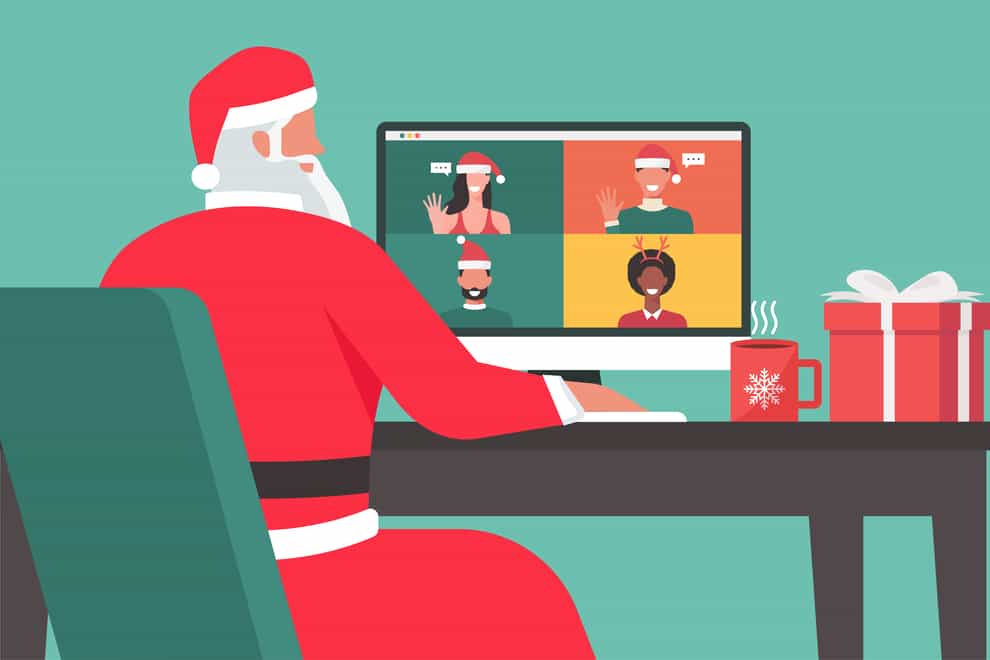 Santa Claus sitting at the desk and using a laptop video calling to people