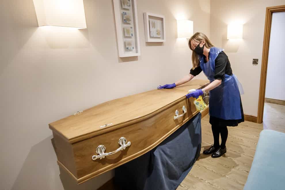 A funeral director disinfects a coffin