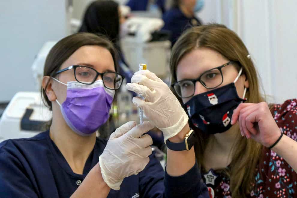 Registered nurse Natalie Chermel, left, and pharmacist Whitney Rader draw a dose of Covid-19 vaccine into a syringe