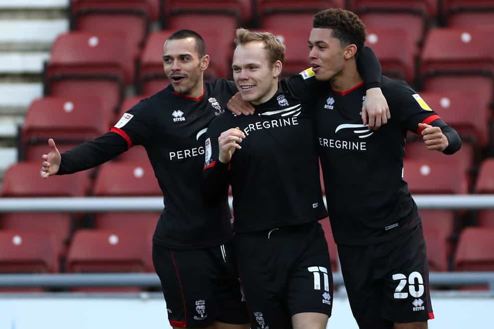Lincoln’s Anthony Scully (centre) celebrates opening the scoring against Northampton