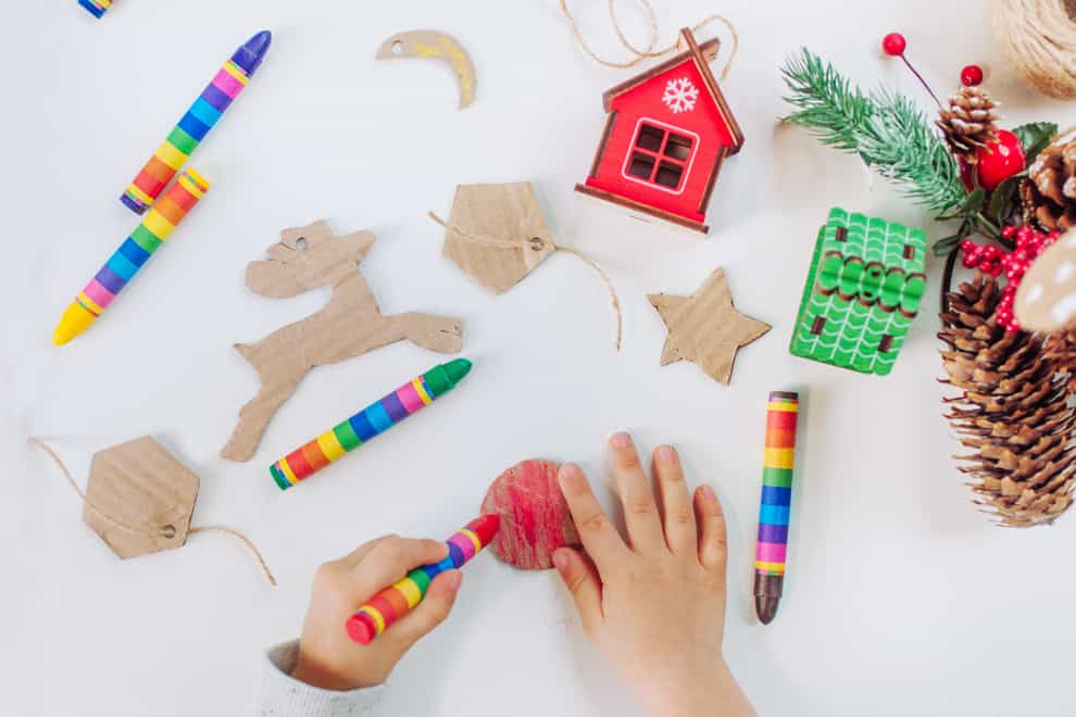 Close up of kids hands drawing handmade corrugated cardboard decorations for Christmas tree
