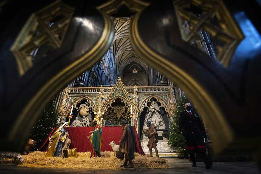 An abbey marshal walks past the Nativity crib and Christmas trees inside Westminster Abbey, London (Victoria Jones/PA)