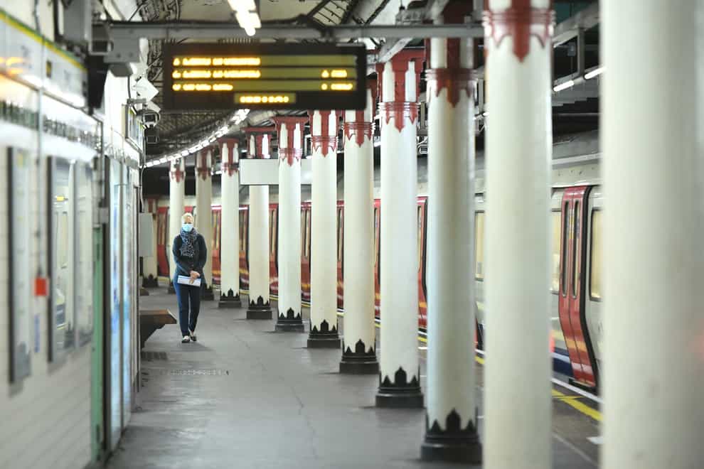 A woman walking along an empty platform at a London tube station