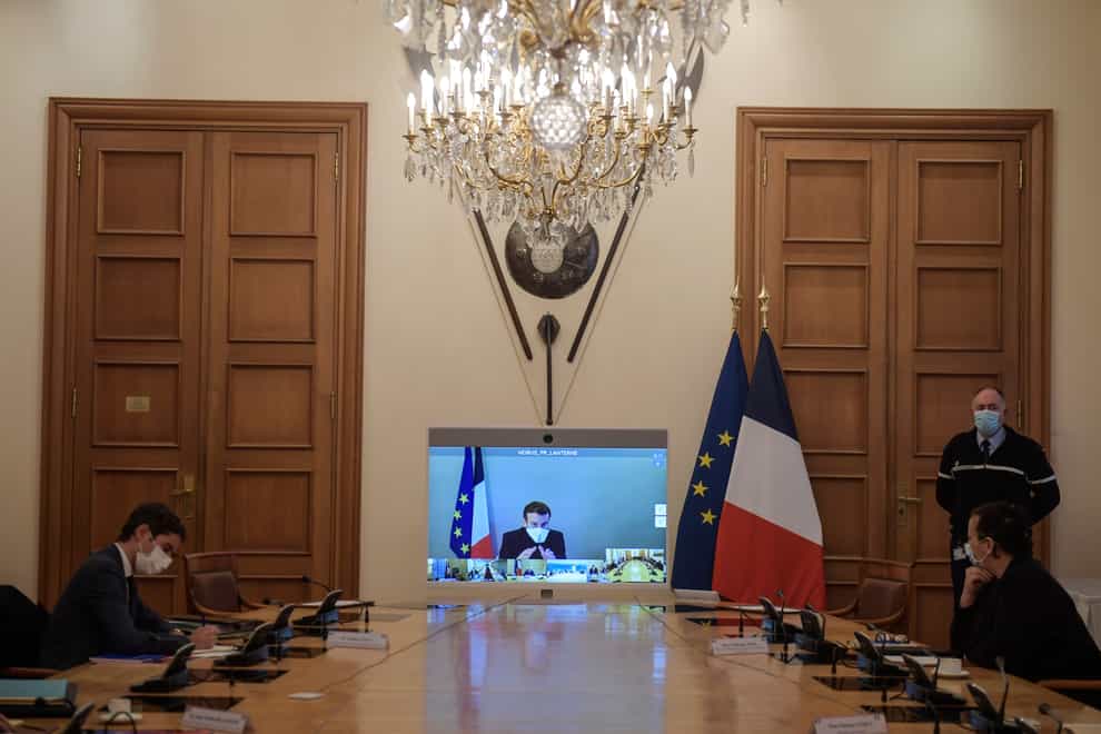 French President Emmanuel Macron is seen on a screen from his presidential residence in Versailles as he attends by video conference the weekly cabinet meeting at the Elysee Palace (Julien de Rosa/AP)